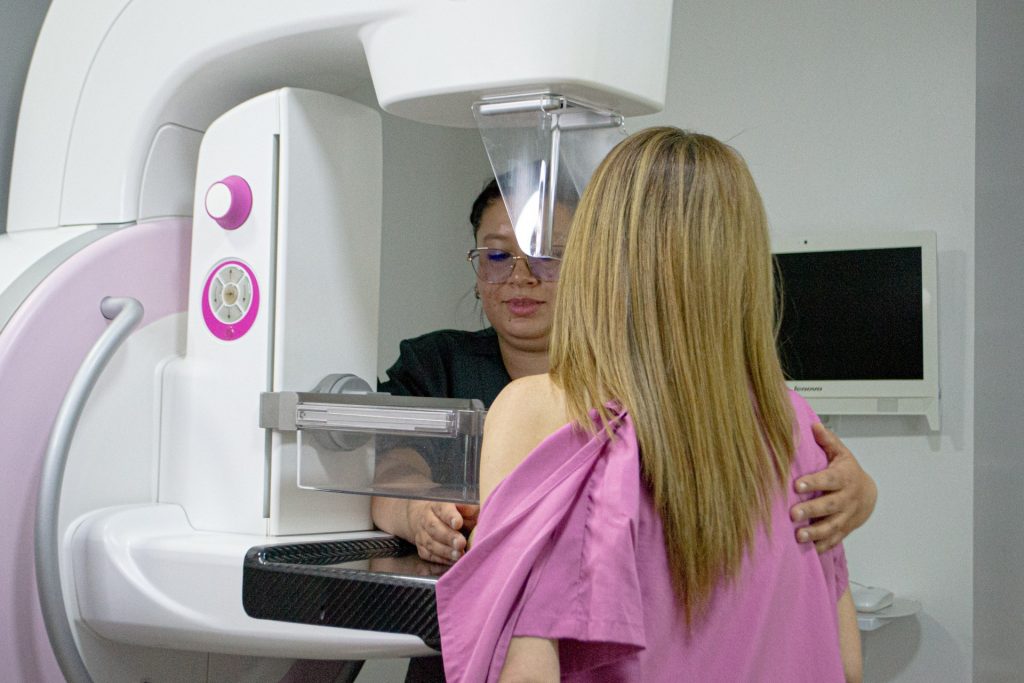 Profesional de salud acompaña a una paciente durante un estudio de mamografía.